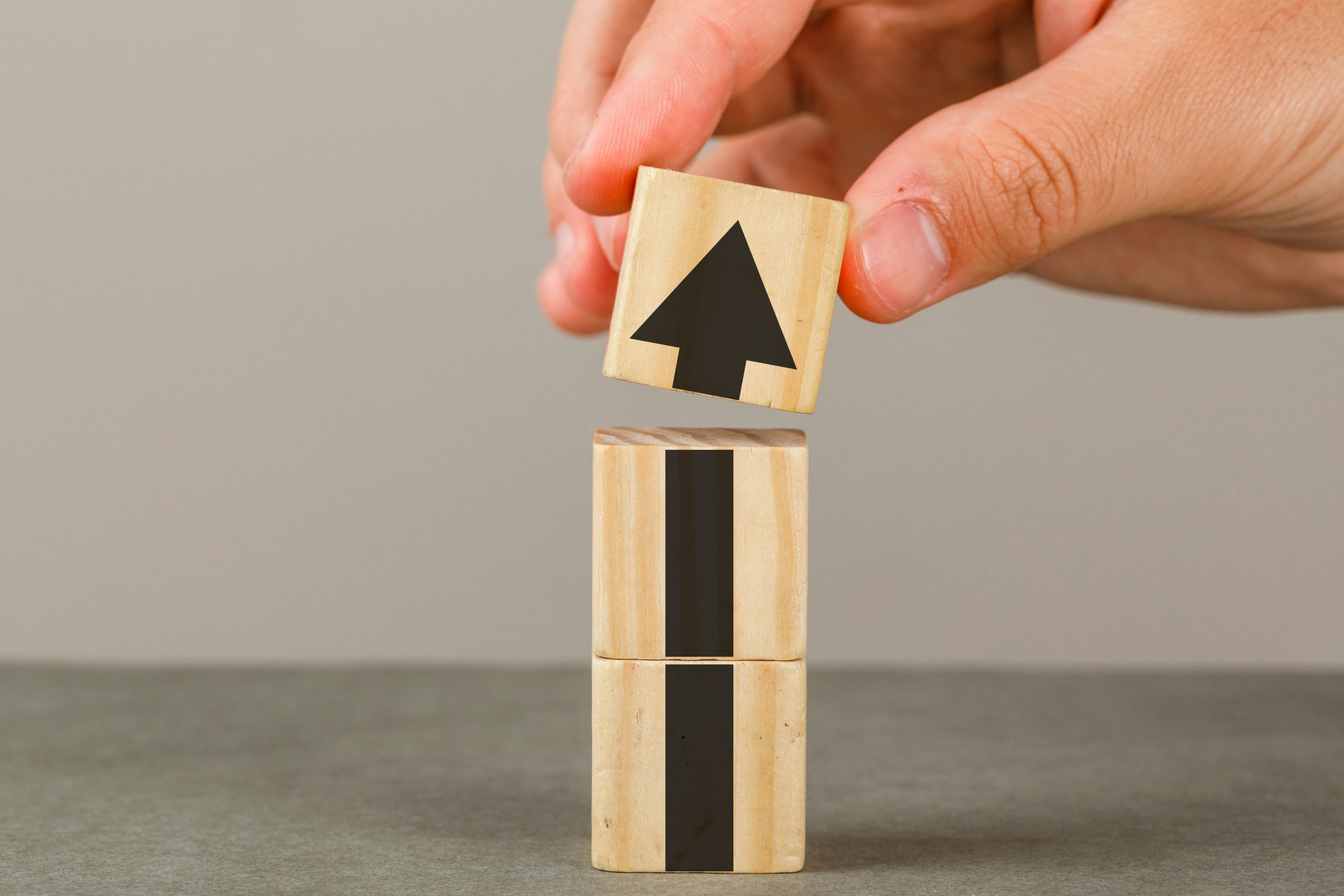 Business growth concept on grey and white background side view. hand putting wood block onto tower.